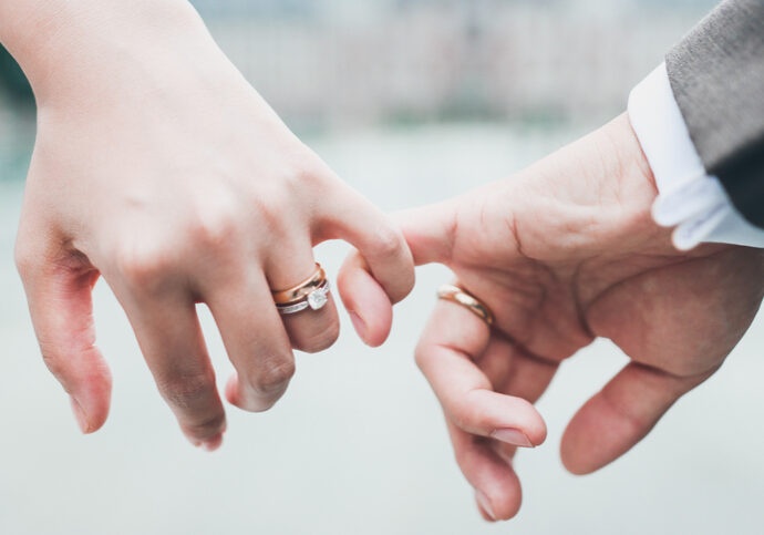 Unrecognizable newlywed couple with interlocked fingers